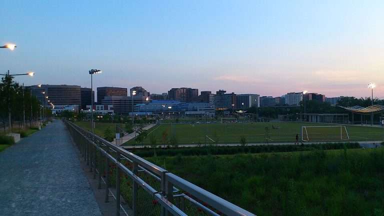 Arlington VA 22 Pathway and soccer field with goalposts under evening sky, city skyline in background.
