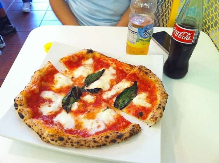 Arlington VA 36 Neapolitan-style pizza with fresh basil and mozzarella on a square plate, accompanied by Coca-Cola and a lemonade bottle.