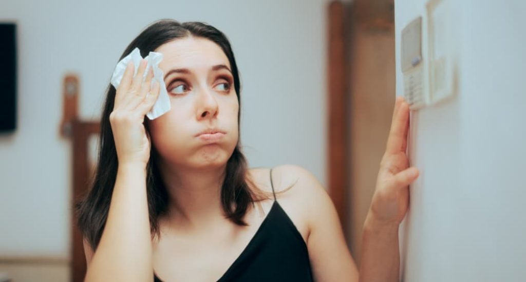 A tenant adjusting the thermostat after learning the apartment air conditioning laws in D.C.