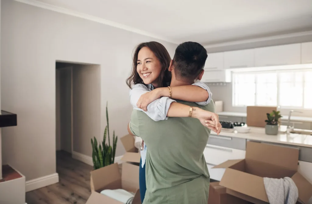 Happy Asian couple dancing in their new home's kitchen.