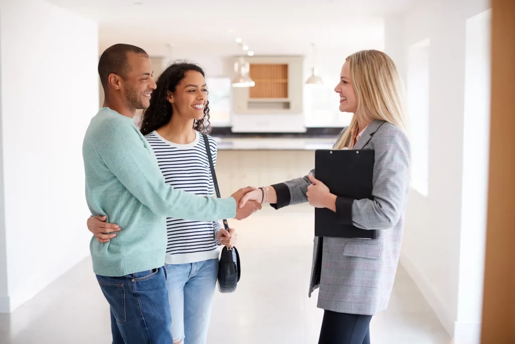 Nomadic real estate agent shaking hands with prospective homebuyers.