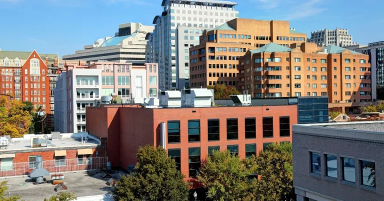 View of modern office buildings and residential apartments in downtown Bethesda, MD, under a clear blue sky, showcasing the city’s urban architecture.